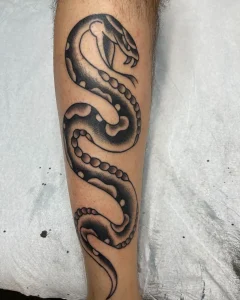 Black and grey snake tattoo wrapped around forearm by San Diego tattoo artist