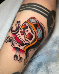 Traditional aviator skull tattoo with red and yellow shading on forearm