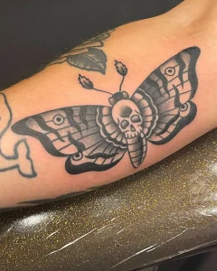 Traditional moth tattoo with skull design in black and grey shading