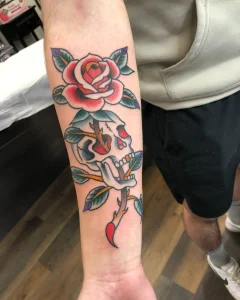 Traditional skull and red rose tattoo on forearm by San Diego tattoo artist